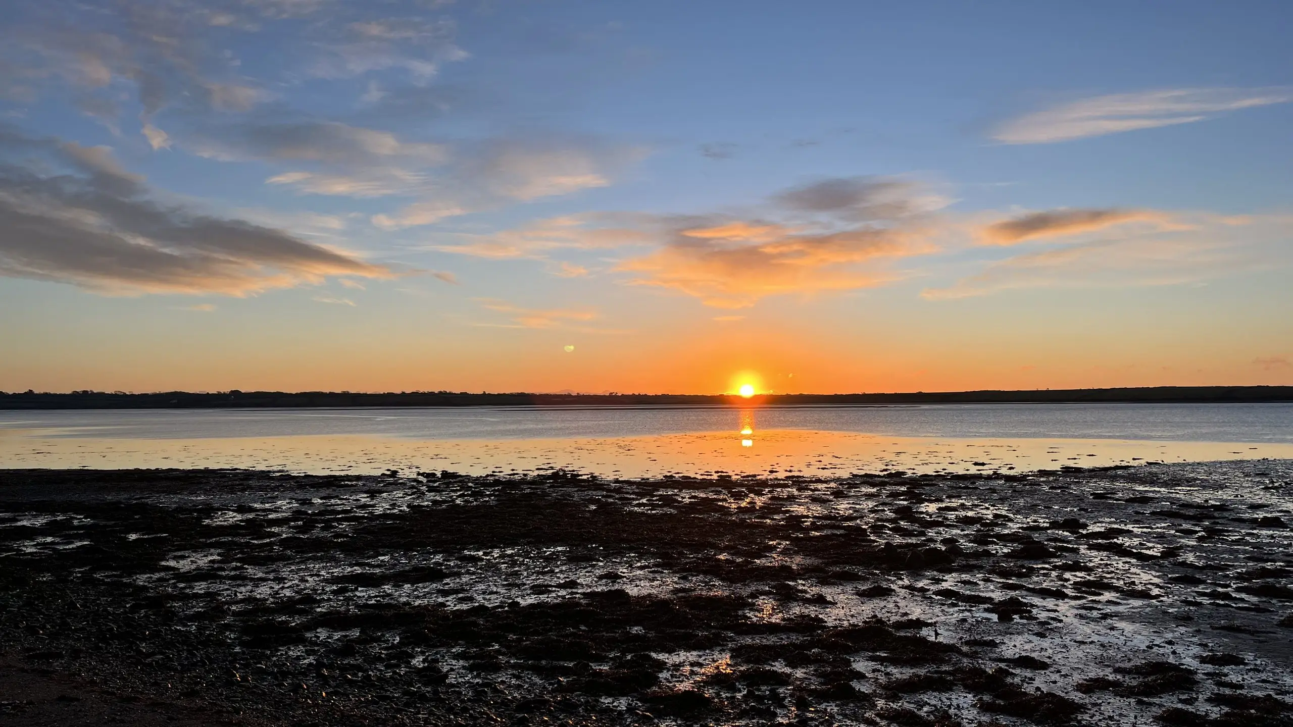 The sun setting over Bannow Bay, the sky washed orange and gold above the dark far shore.