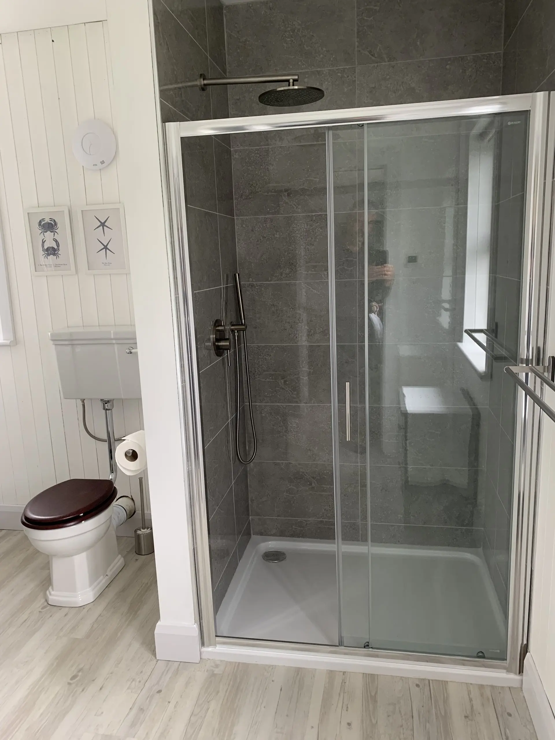 A bathroom with a glazed shower cubicle beside the toilet, and a window looking to the garden.