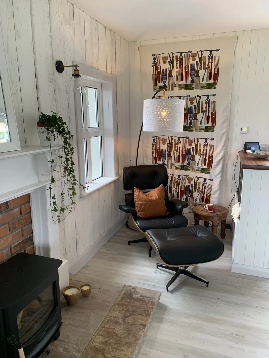 A black leather lounge chair and footstool in the reading nook, beside a window.